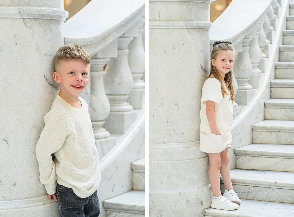 A young brother and sister lean against a column at the bottom of the grand marble staircase inside the Utah State Capitol building