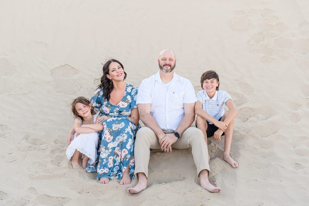 a summer portrait of a mother, father, daughter, and son sitting in the sand at Little Sahara in Nephi