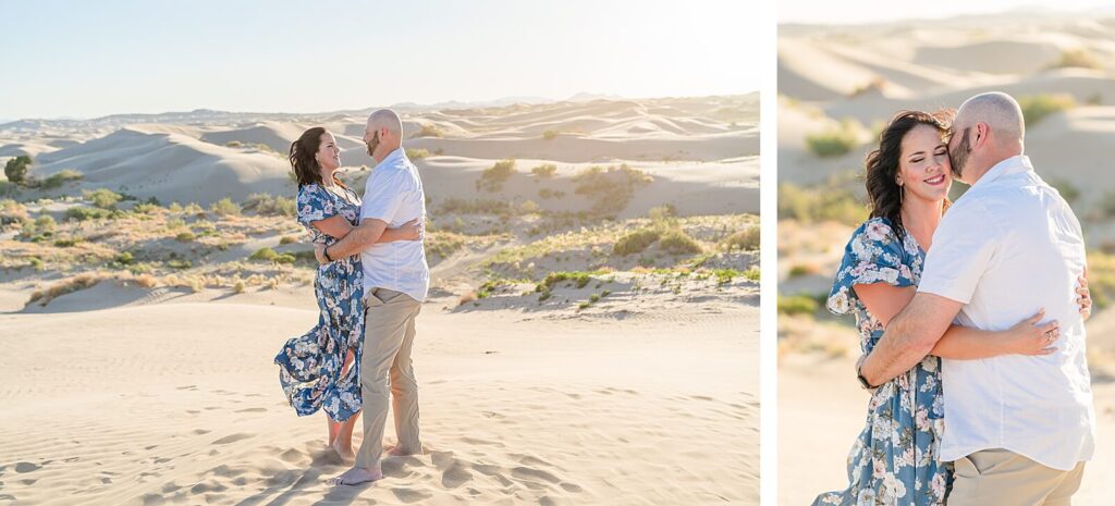 a husband wearing a white button-down shirt and khaki pants embraces his wife wearing a long blue dress as they stand on a sand dune at Little Sahara, Nephi