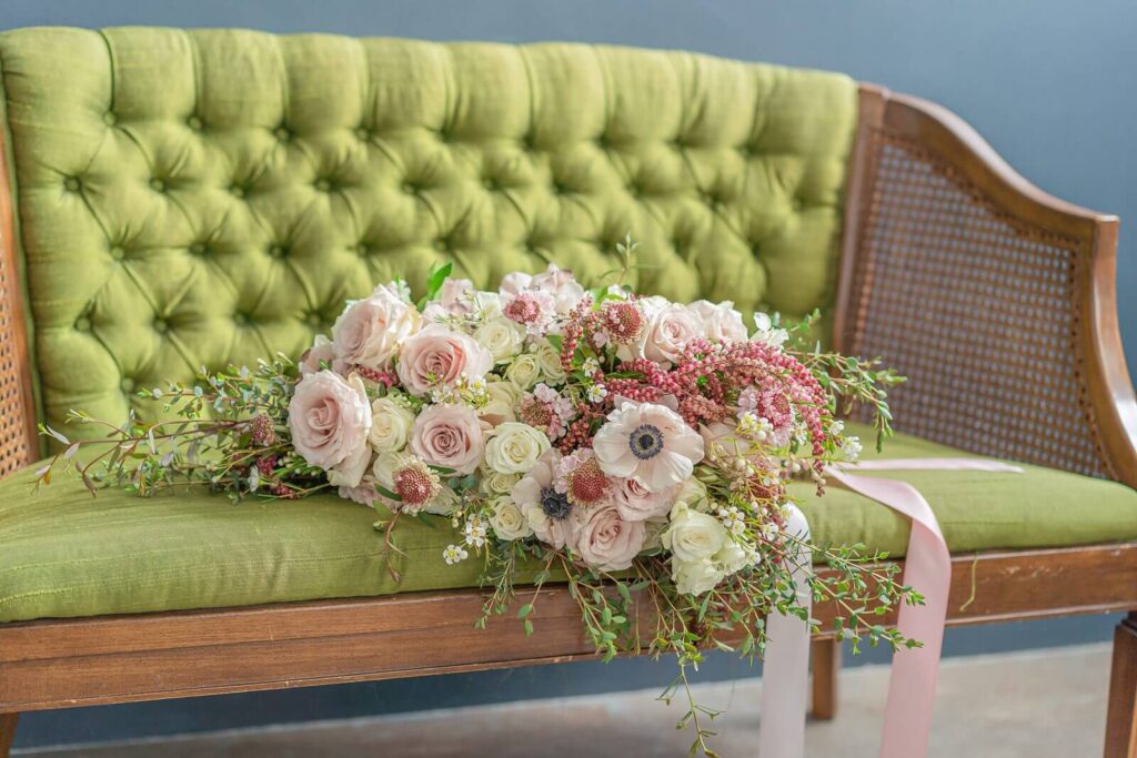 a wedding bouquet with pink and white roses on an olive green chair at a photography studio in downtown Salt Lake City