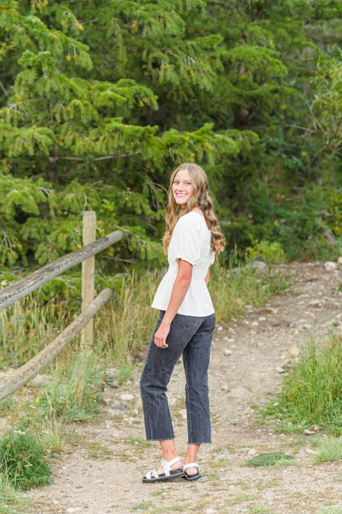 a pleasant grove high school senior girl looks back at the camera as she walks along a trail in American Fork Canyon