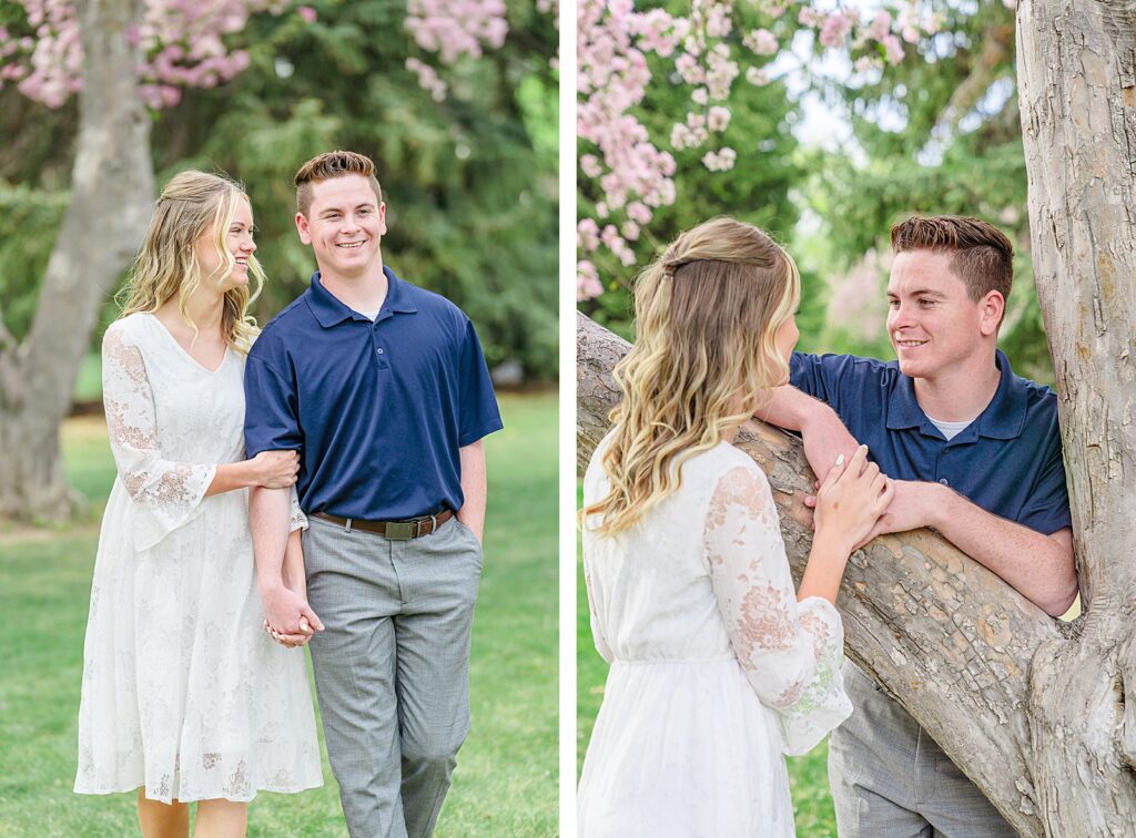 a woman in a white lace dress smiles at her fiancé wearing a navy blue polo shirt and gray slacks as they walk in Quail Cove Park